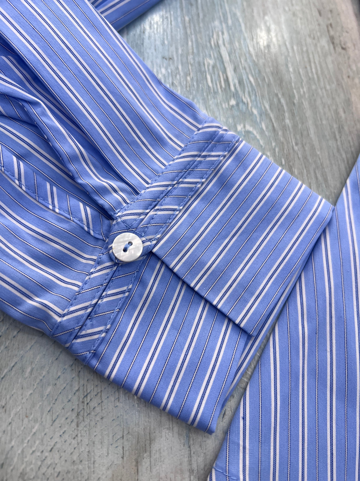 Camicia donna a righe celeste e bianco Coroa – vestibilità avvitata, taglio punto vita con fondo ampio - dettaglio polsi e fantasia tessuto.