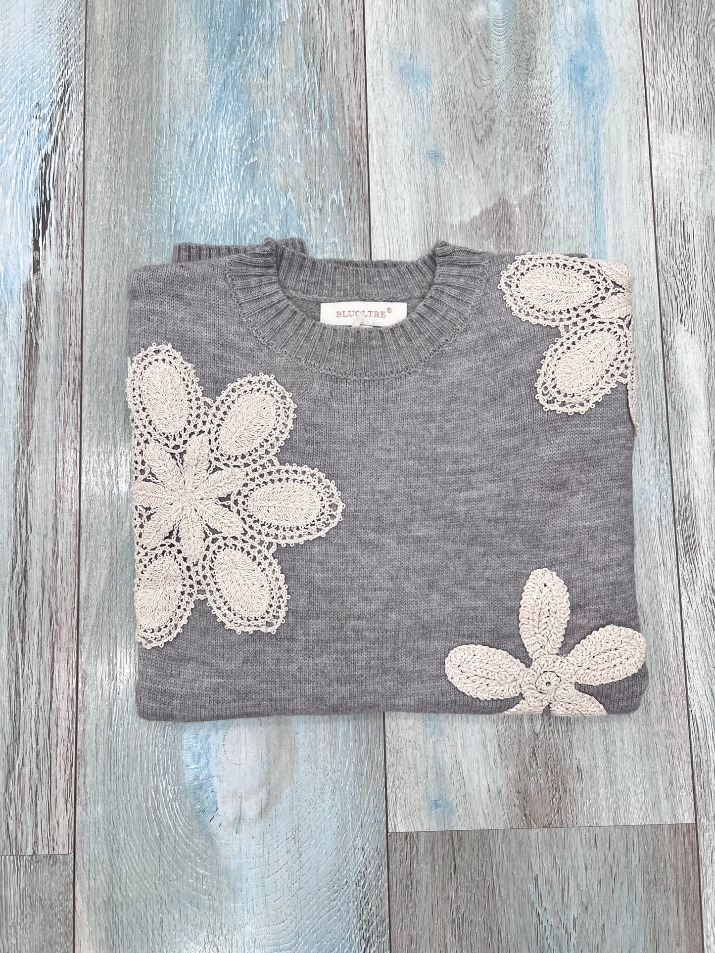 Dettaglio fiori all'uncinetto su maglione donna invernale