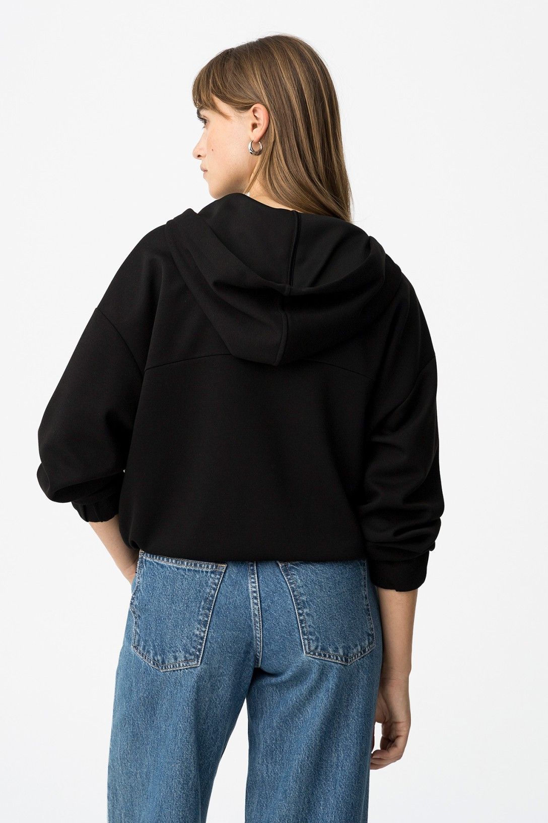 "Felpa Zip & Cappuccio nera vista dal retro - Silhouette con cappuccio e styling con jeans vintage"