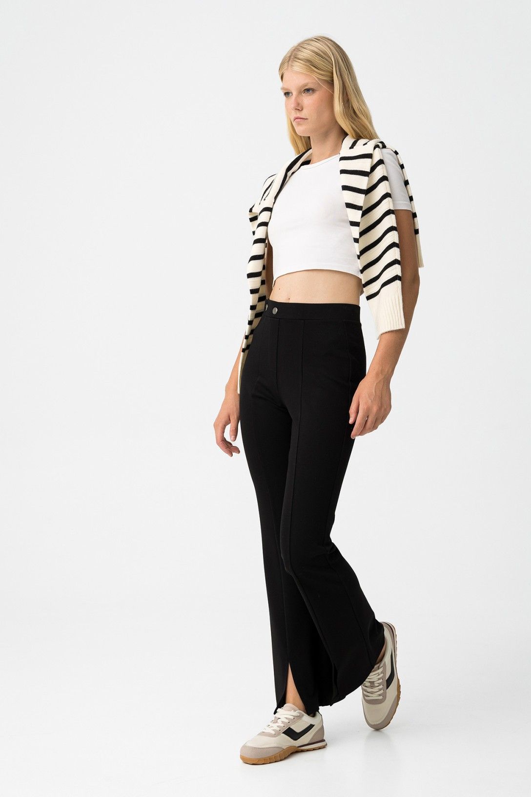 Look completo con leggings zampa neri Tiffosi, gamba svasata e orlo con spacco, styling casual con sneakers
