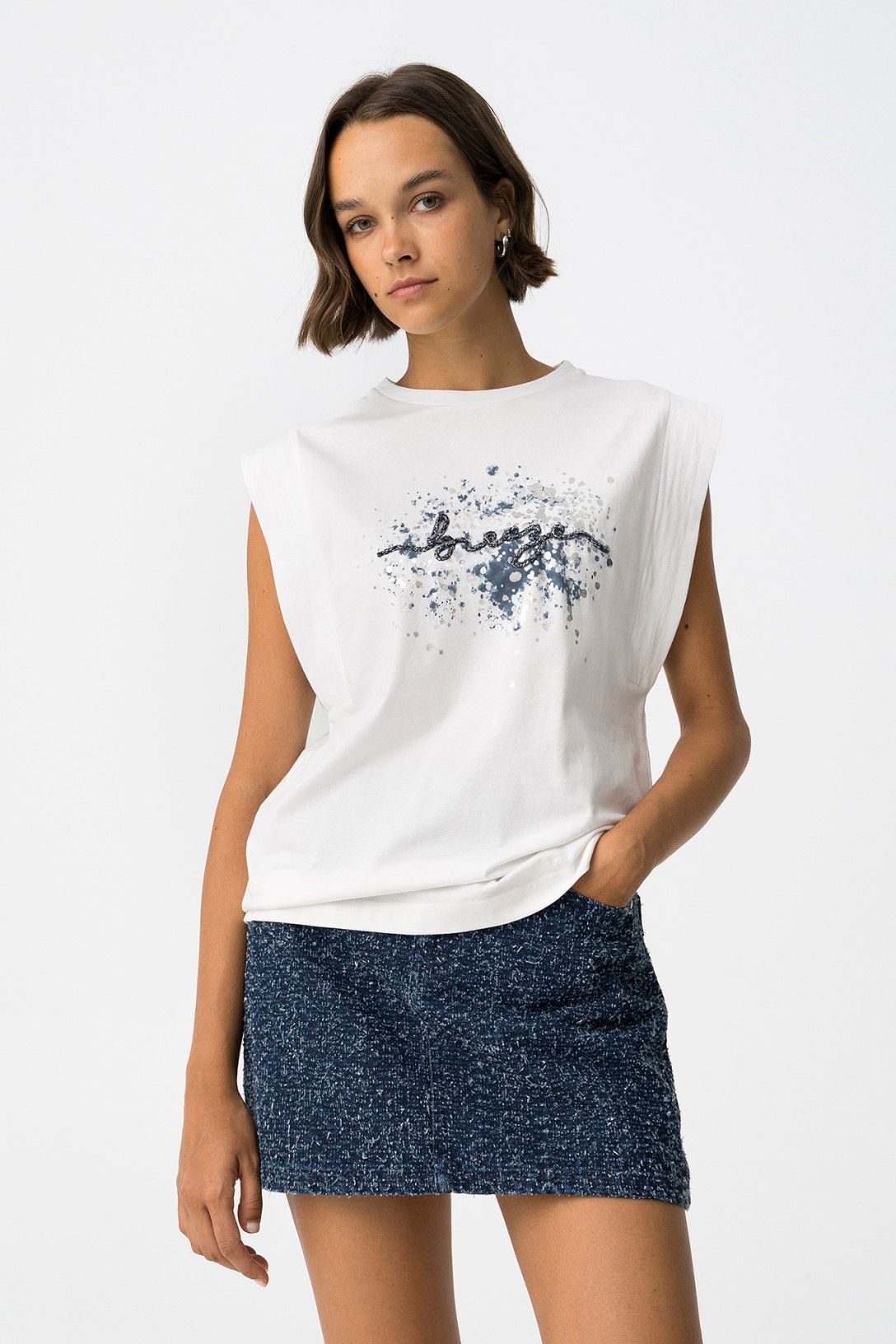 T-shirt bianca Indigo con stampa frontale blu e scritta decorativa, senza maniche oversize abbinata a minigonna denim