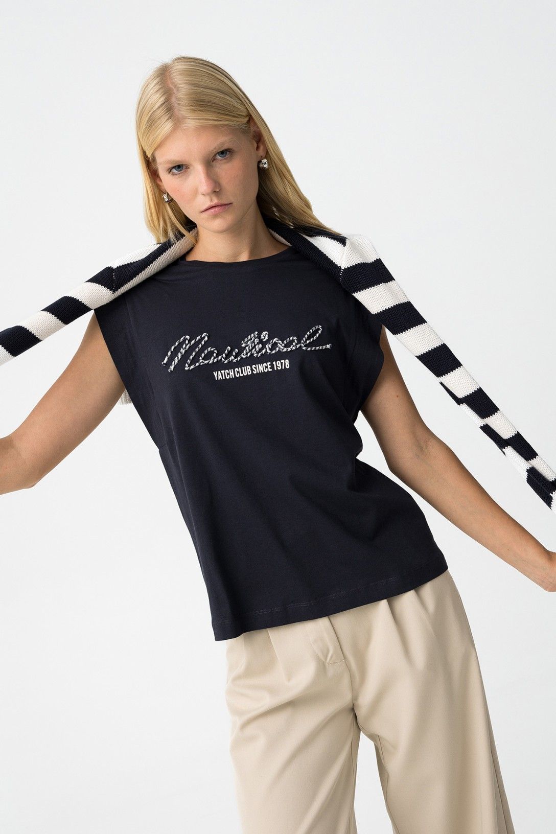 T-shirt blu navy Indigo con scritta "Yatch Club Since 1978", senza maniche oversize abbinata a pantaloni beige e cardigan a righe