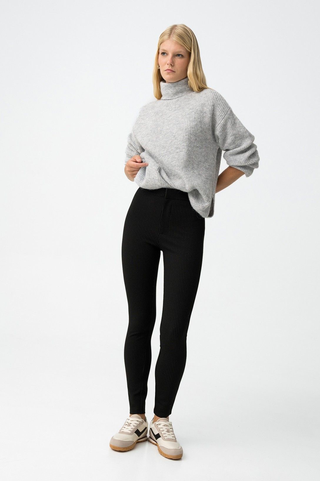 Leggings Marylin nero gessato - modella indossa leggings con maglione grigio collo alto e sneakers bianche