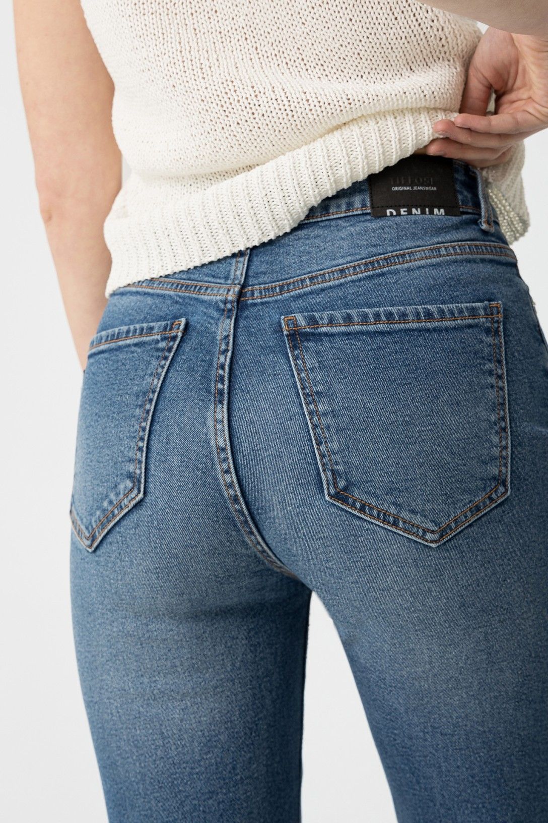 "Vista ravvicinata delle tasche posteriori dei jeans Mom_Slim_39 con etichetta DENIM visibile e cuciture dorate"