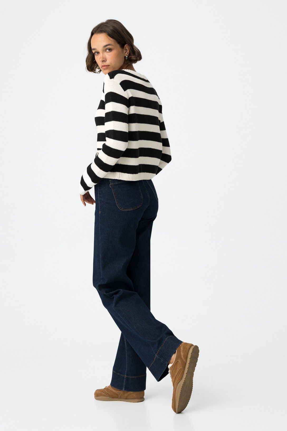 Jeans Olivia blu scuro vista laterale, silhouette gamba dritta comfort fit abbinati a cardigan a righe e sneakers