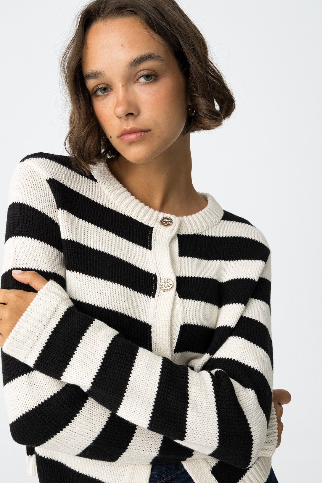 Dettaglio cardigan Requiem a righe orizzontali bianco e nero, bottoni metallici dorati, scollo rotondo e vestibilità regolare