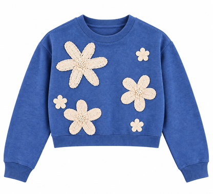 Maglia donna crop azzurra 8090 su fondo bianco, con girocollo, maniche lunghe e cinque applicazioni floreali color panna con dettagli perlati sul davanti.