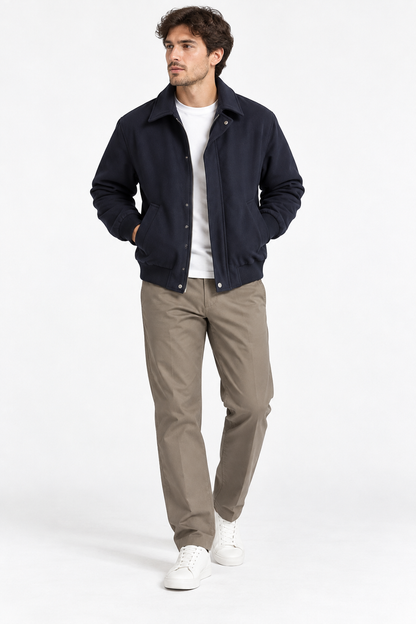 Giacca, cappotto uomo Cohen blu scuro indossata aperta, abbinata a maglia bianca, pantaloni beige e sneaker bianche.