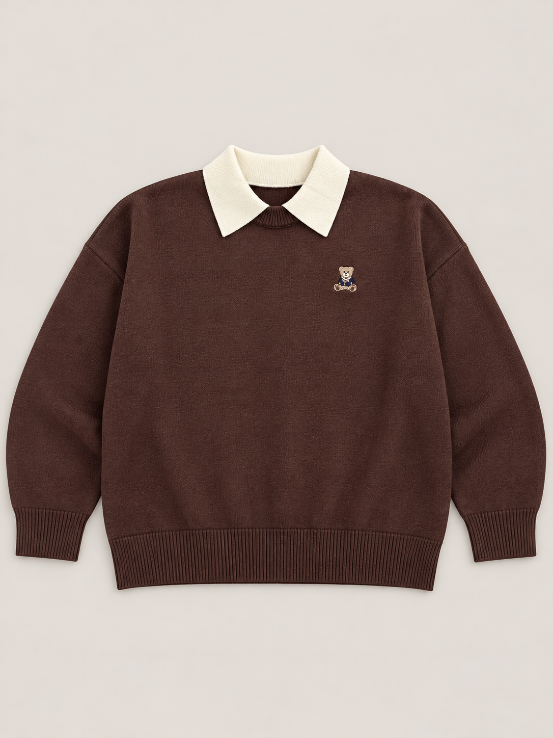 Maglione donna Teddy cioccolato steso in piano, con colletto panna, ricamo orsetto, maniche lunghe e bordi a costine.
