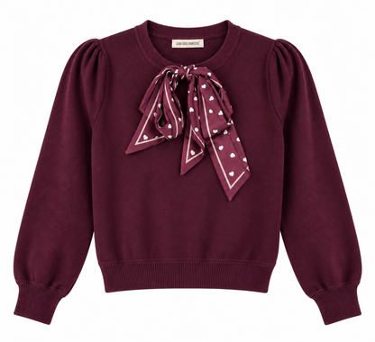 Maglia donna 894 bordeaux su fondo bianco, con girocollo, maniche lunghe a sbuffo, fondo elasticizzato e foulard bordeaux a cuori bianchi annodato sul davanti.