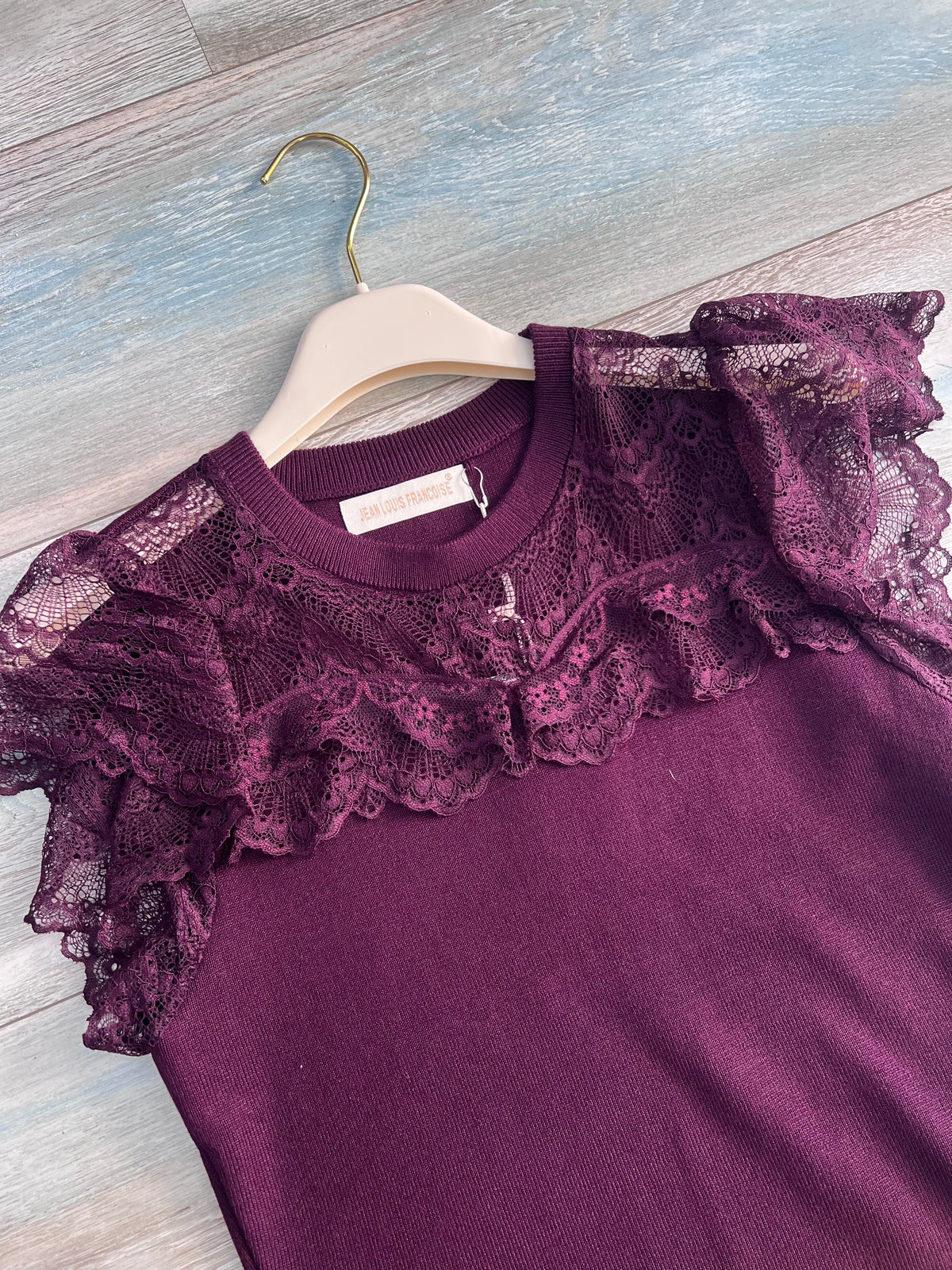 Dettaglio del top donna bordeaux con pizzo traforato, bordo smerlato e manica corta con volant