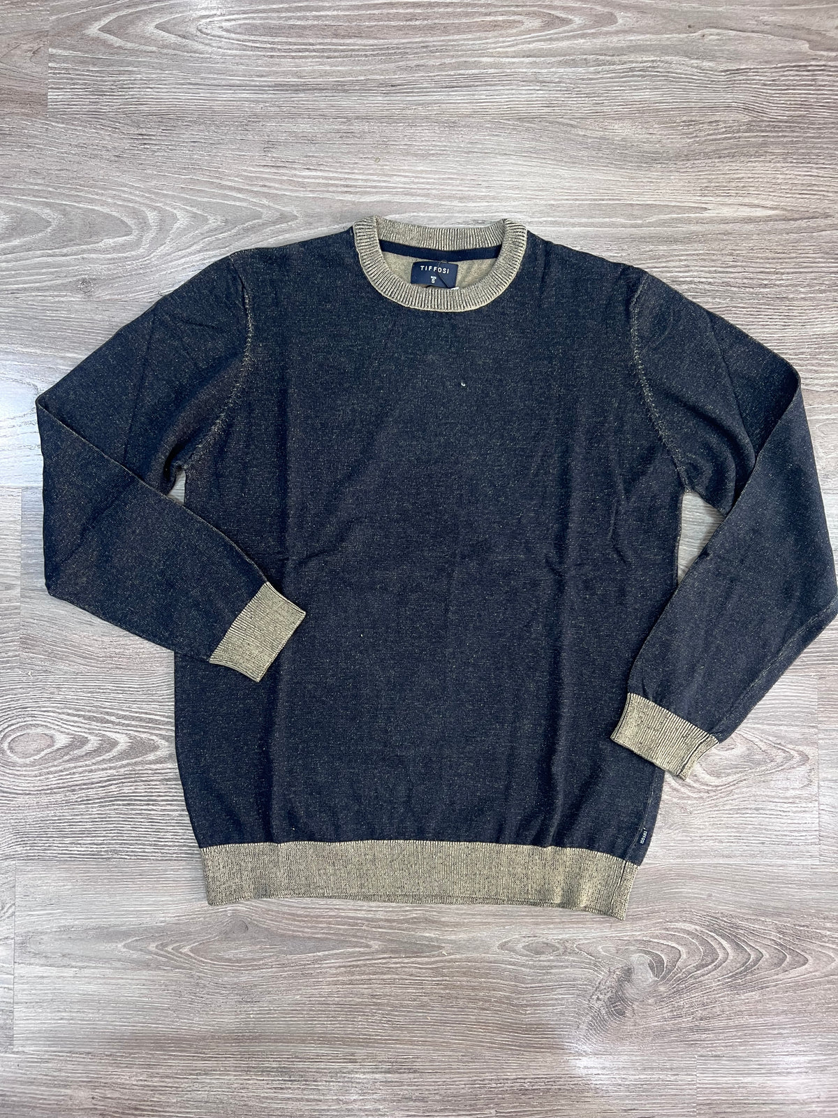 Maglia uomo Tadeu blu melange stesa su fondo effetto legno, con girocollo, maniche lunghe e bordi beige a contrasto