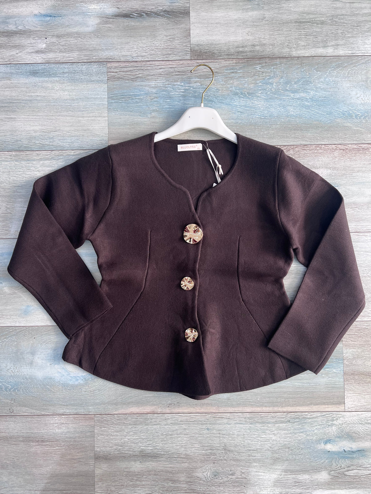 Cardigan donna 872 color cioccolato steso su fondo effetto legno, con tre bottoni gioiello, maniche lunghe, tasche laterali e fondo svasato
