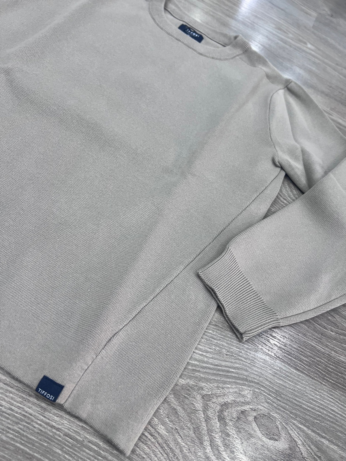 Dettaglio del maglione uomo Enzo Tiffosi grigio, con trama del tessuto, cucitura laterale sagomata, polso a coste e logo del brand