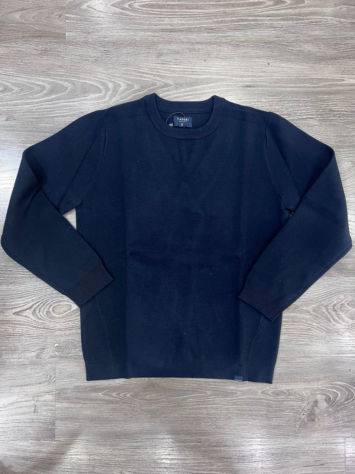 Maglione uomo Enzo Tiffosi blu scuro steso su fondo effetto legno, con girocollo, maniche lunghe, polsi e fondo a coste