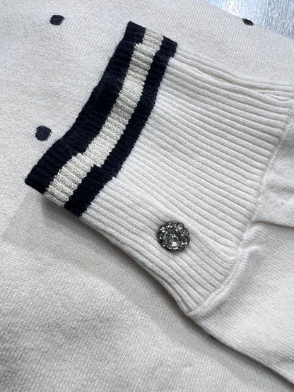 Dettaglio del polsino della maglia 516 Bluoltre color panna, con righe nere, apertura laterale e bottone gioiello.
