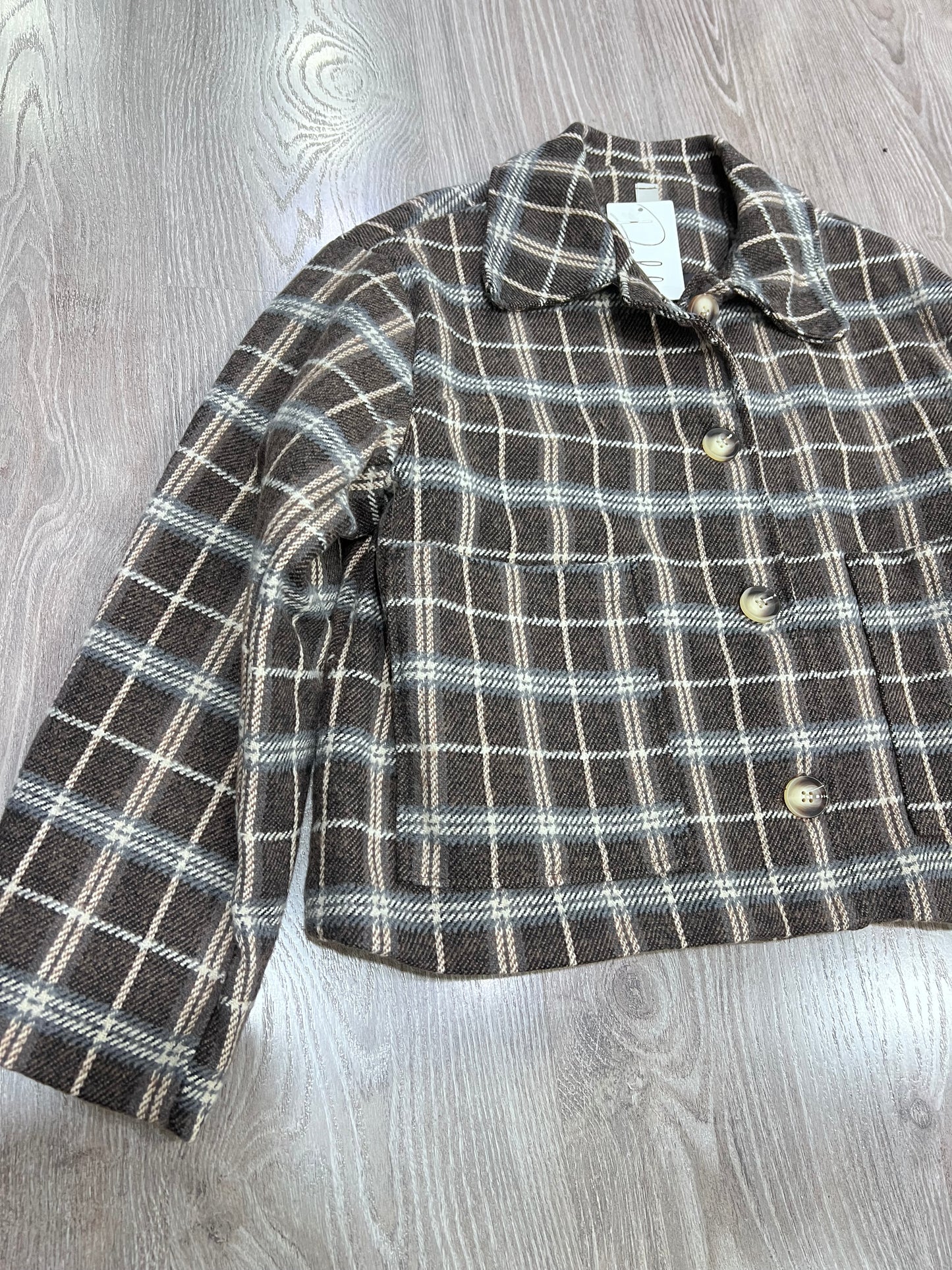 Dettaglio colletto revers e abbottonatura giacca tweed a quadri donna
