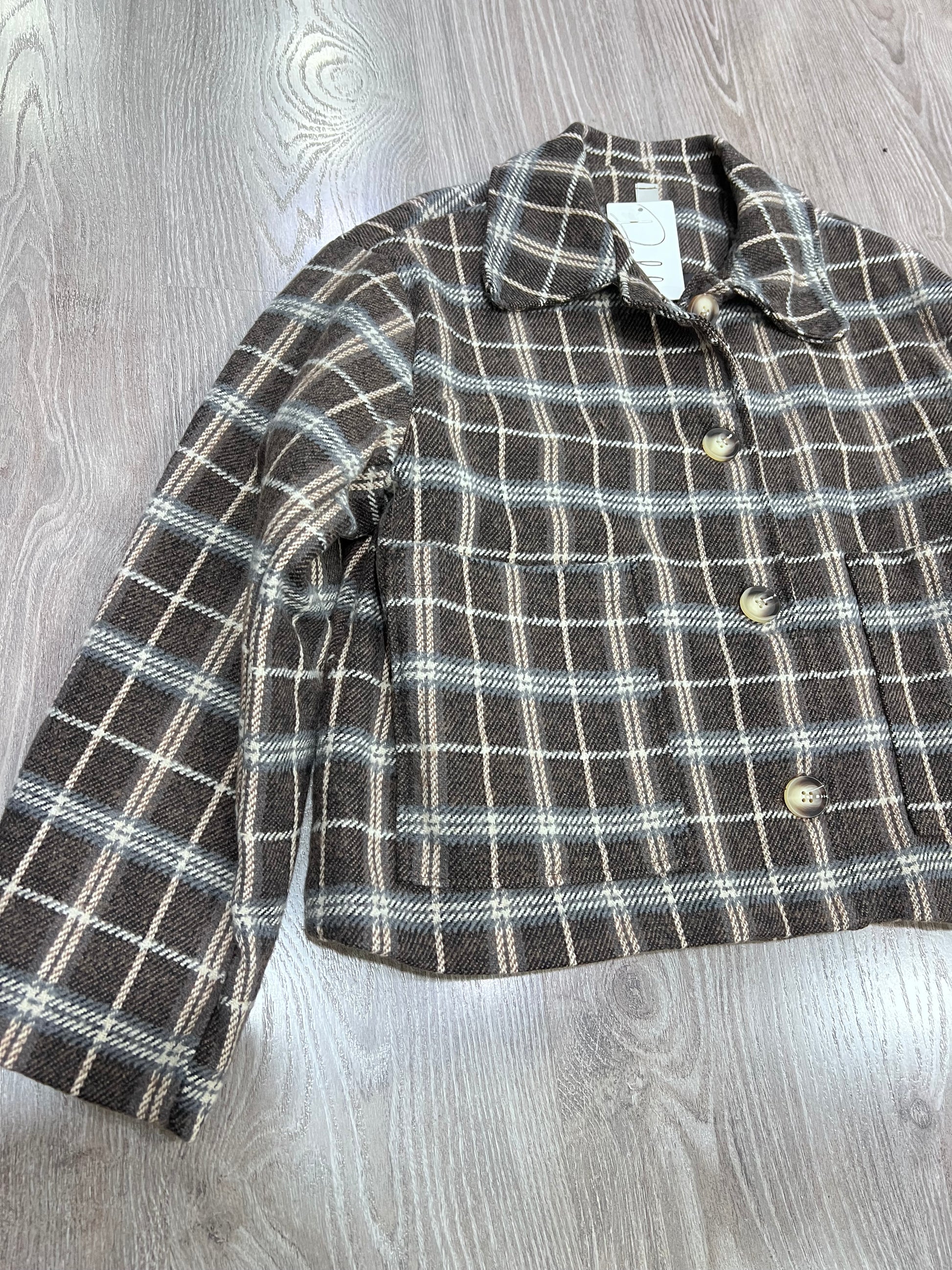 Dettaglio colletto revers e abbottonatura giacca tweed a quadri donna
