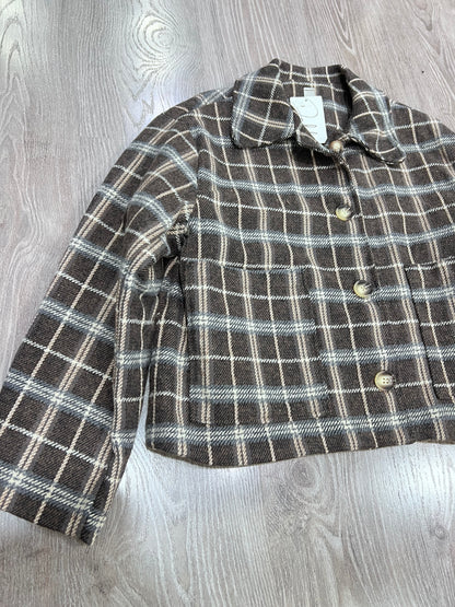 Dettaglio colletto revers e abbottonatura giacca tweed a quadri donna
