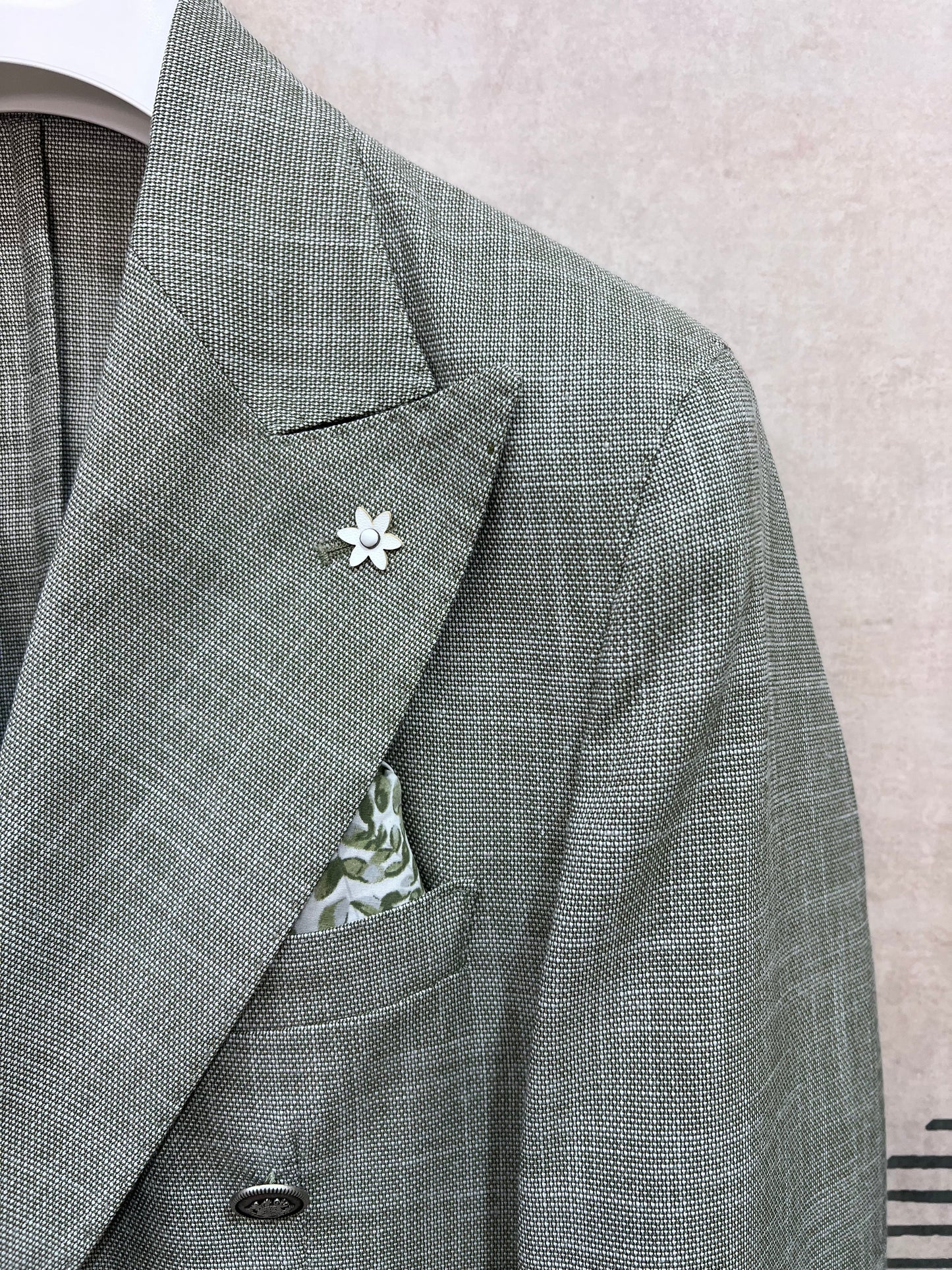 Dettaglio rever giacca doppio petto verde fiammato — trama fiammata effetto lino, spilla fiore bianca e pochette floreale, sartoria Made in Italy dell'abito uomo doppio petto verde