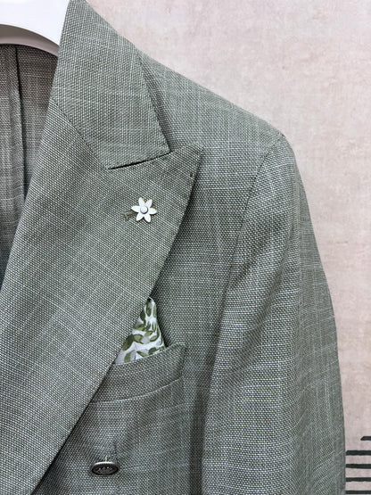 Dettaglio rever giacca doppio petto verde fiammato — trama fiammata effetto lino, spilla fiore bianca e pochette floreale, sartoria Made in Italy dell'abito uomo doppio petto verde