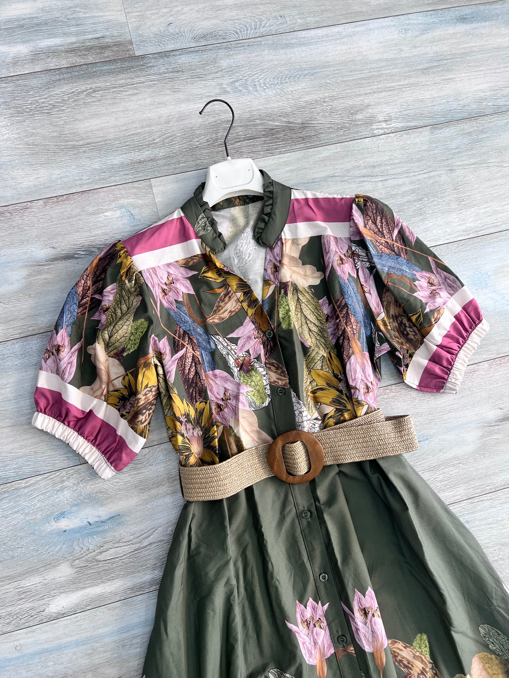 Dettaglio busto abito donna militare: collo coreana con scollo a V, mezza manica con polsino a righe fucsia e elastico arricciato, fantasia botanica con fiori rosa e foglie gialle su fondo verde, cintura in rafia, cotone Made in Italy
