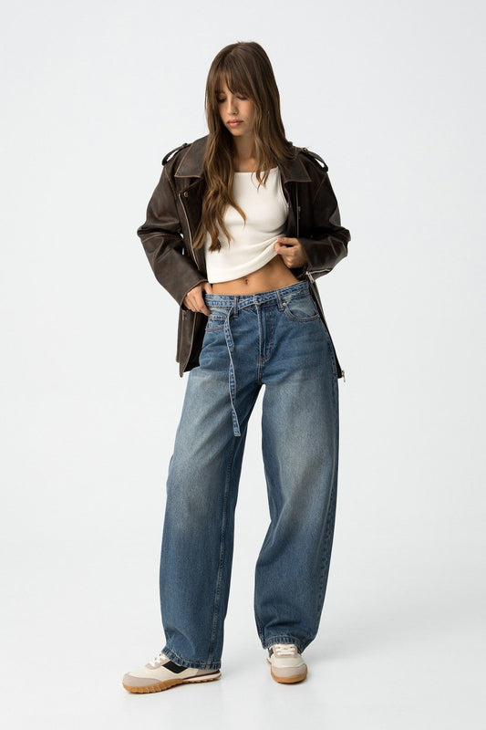 Modella con jeans balloon Ava_2 blu, top bianco e giacca di pelle nera - look street style che mostra la silhouette a gamba a palloncino