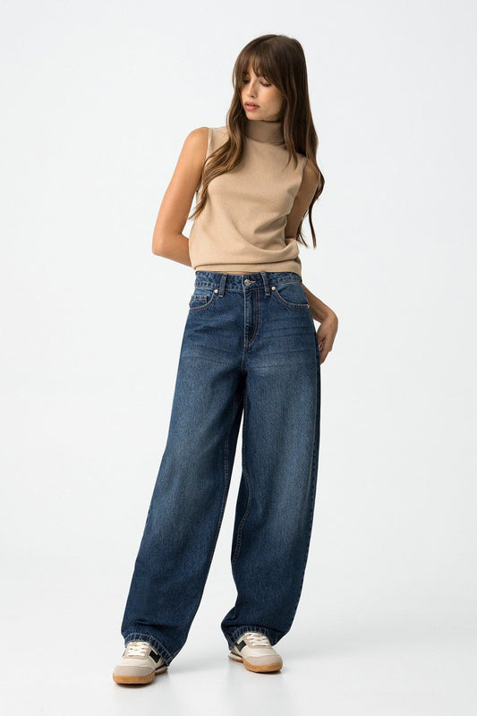 Modella indossa jeans balloon vita alta con dolcevita beige e sneakers bianche
