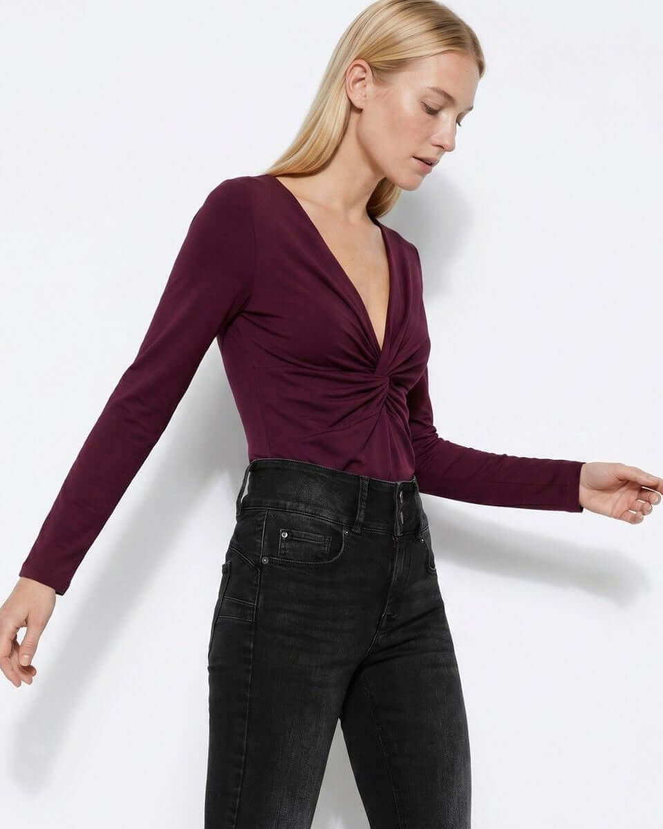 Top donna amarena Tiffosi Chrissy indossato – vista laterale con jeans neri skinny, dettaglio nodo frontale e scollo V profondo
