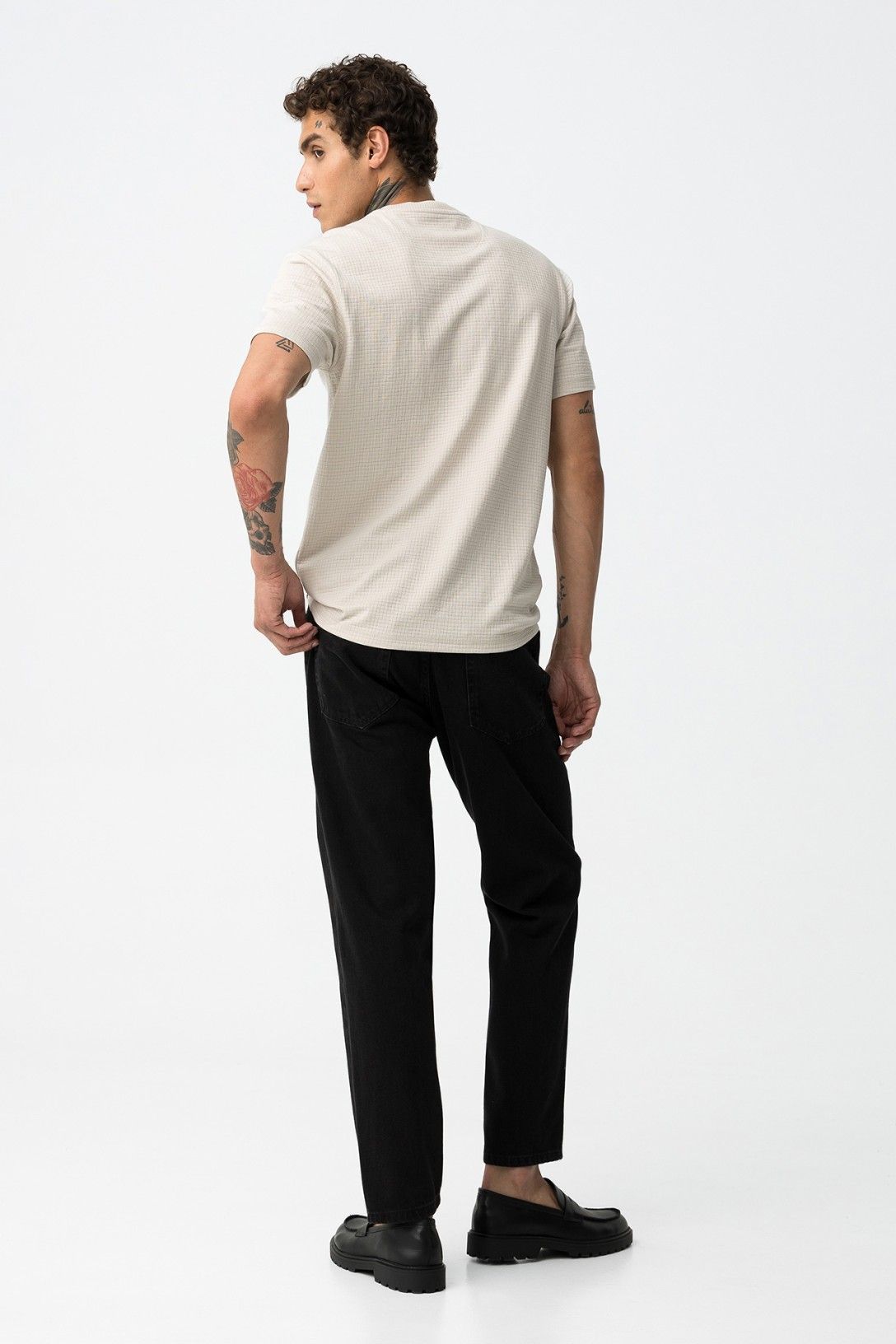 Vista posteriore del modello con t-shirt beige - evidenzia la vestibilità comoda e rilassata dei jeans neri cole_67