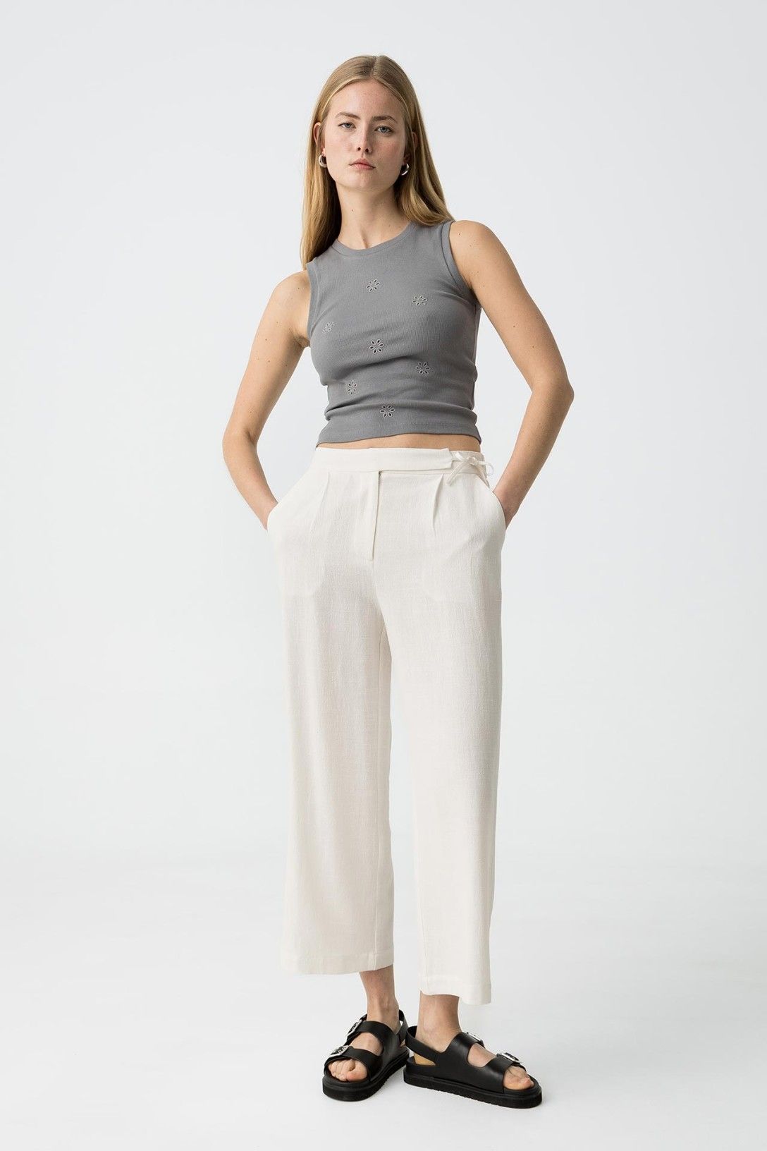 "Donna indossa Pantalone Capri JULIE bianco in lino e viscosa, vista frontale completa con top grigio decorato, sandali neri, look casual elegante"