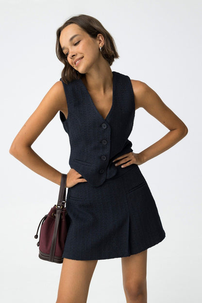 Cord Set Mana blu navy completo donna con gilet senza maniche e gonna corta, bottoni frontali e borsa bordeaux, look elegante
