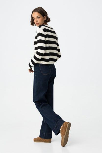 Jeans Olivia blu scuro vista laterale, silhouette gamba dritta comfort fit abbinati a cardigan a righe e sneakers
