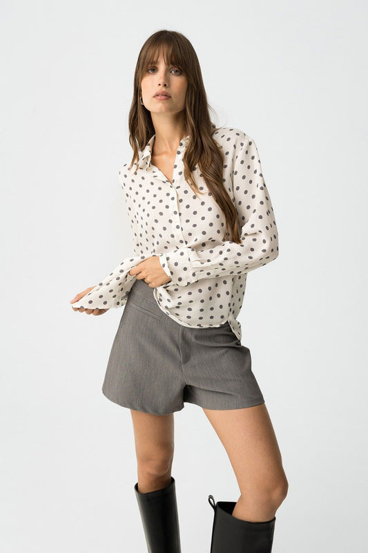Donna che indossa camicia Paradise_3 bianca a pois grigi, abbinata a shorts grigi e stivali neri - look completo
