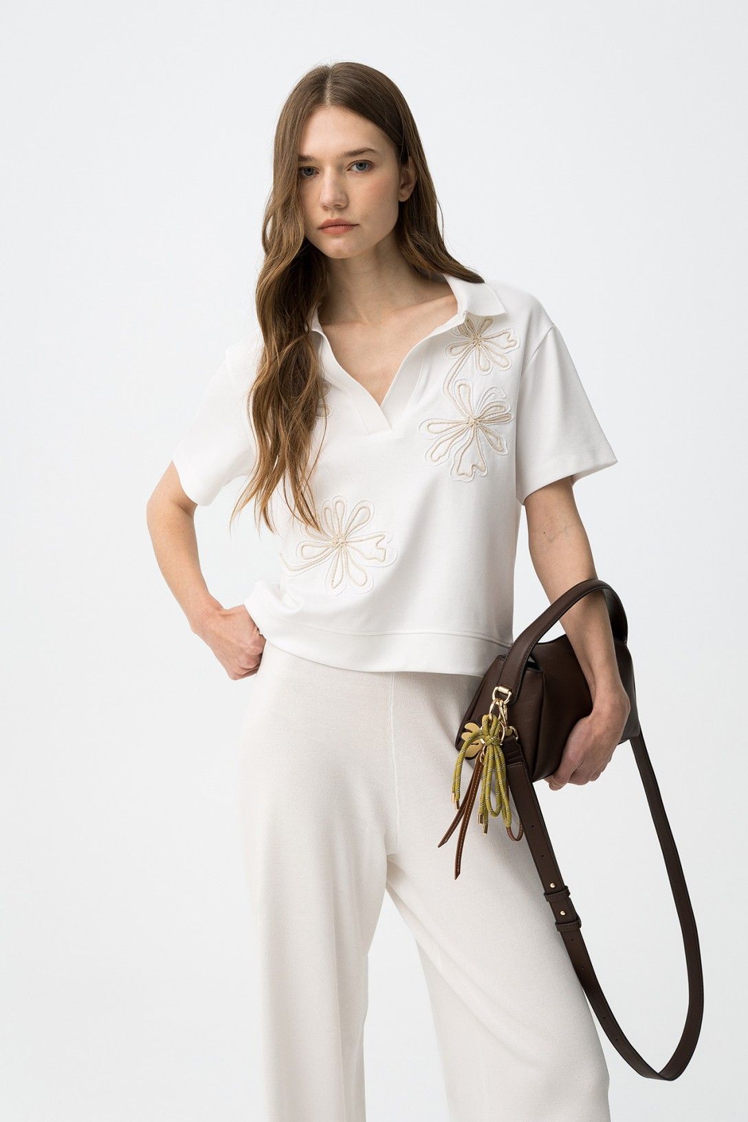 Donna indossa polo donna ricamo floreale  Philly bianca con ricamo floreale, mezza manica e scollo a V - look completo