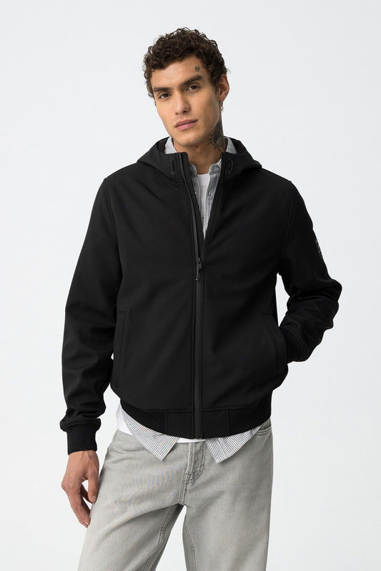 Uomo che indossa giubbotto Pryor nero Tiffosi con cappuccio e zip, abbinato a camicia a righe e jeans grigi
