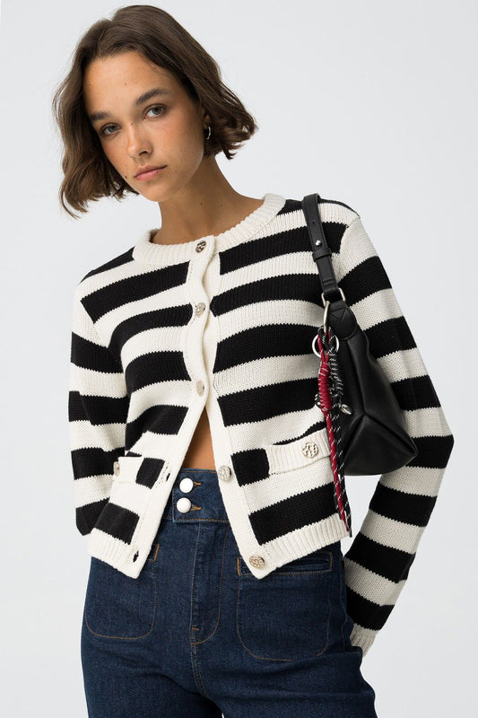 Cardigan Requiem a righe bianche e nere con bottoni metallici, donna indossa jeans vita alta e borsa nera, look casual chic
