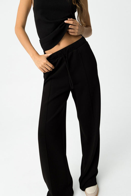 Donna che indossa pantalone tuta nero wide leg Valentina con top nero, vista frontale dettaglio vita alta con coulisse
